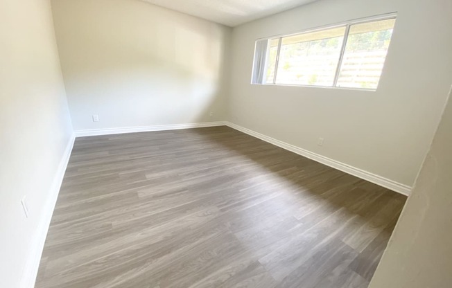 an empty room with wooden floors and a window