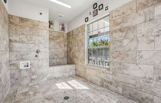 A bathroom with a marble tile shower and a window.