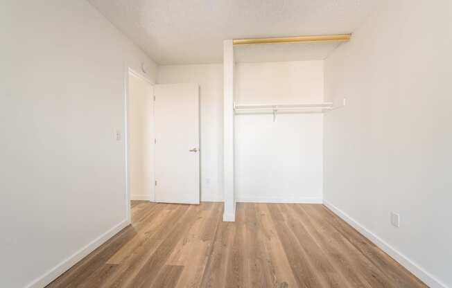 a bedroom with hardwood floors and white walls