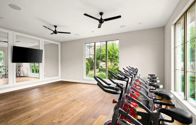 the home gym has a wall of windows and a row of exercise bikes