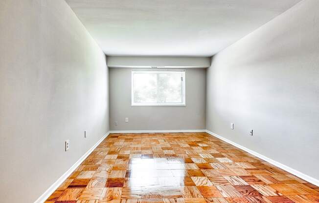 an empty room with wood floors and a window