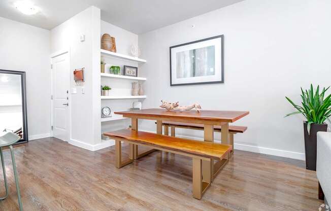 A room with a wooden table and bench, a chair, and a potted plant.