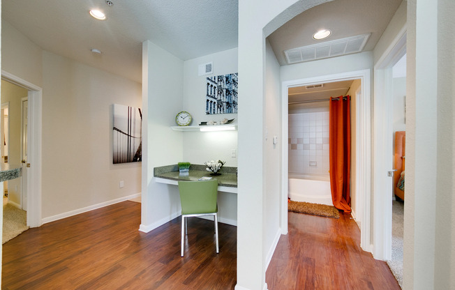 View of Upgraded Apartment Interior, Showing Living Room with Built-In Desk, and View of Bedroom and Bathroom at Stonebriar of Frisco Apartments