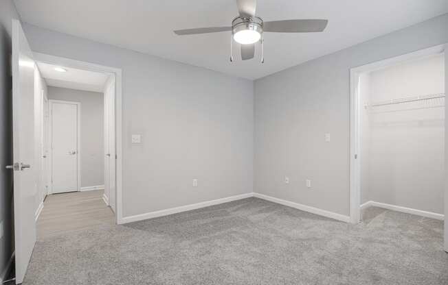 an empty bedroom with a ceiling fan and a door to a closet