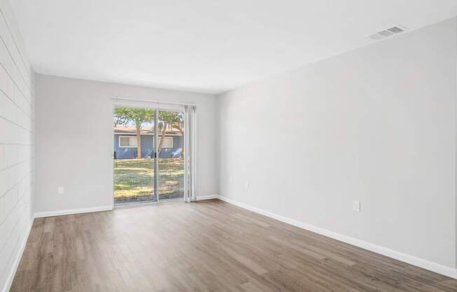A room with a sliding glass door leading to a backyard.