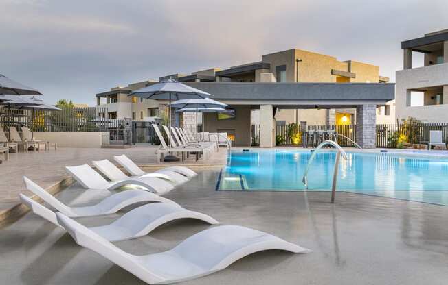 a pool with white lounge chairs and umbrellas