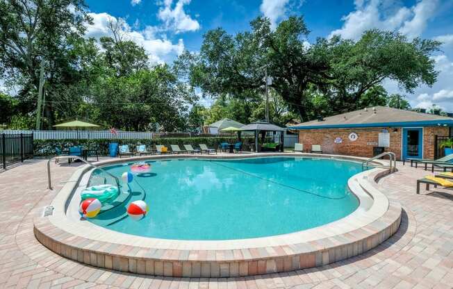Community pool at Watermarc Apartments in Lakeland, FL with tile flooring, inflatable pool toys, and large pool house.