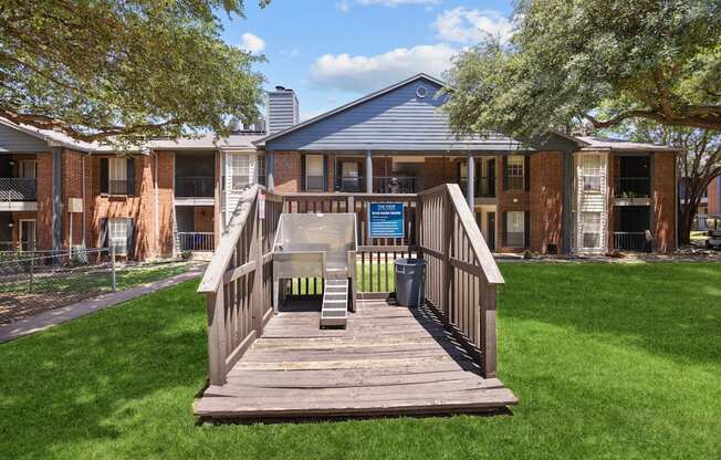 A wooden deck leads to a building with a blue roof.