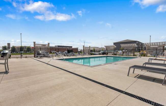 A large outdoor swimming pool with a concrete deck and a building in the background.