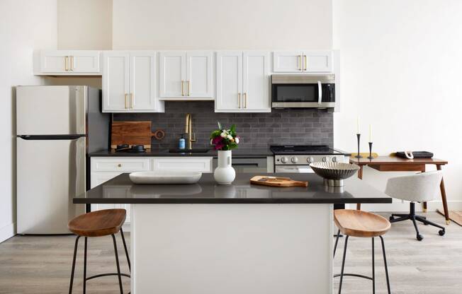 a kitchen with white cabinets and a black counter top