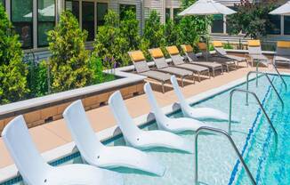 A pool with white chairs and a building in the background.
