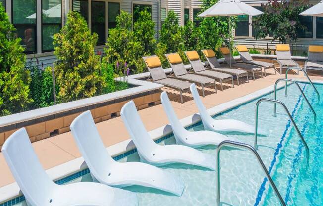 A pool with white chairs and a building in the background.