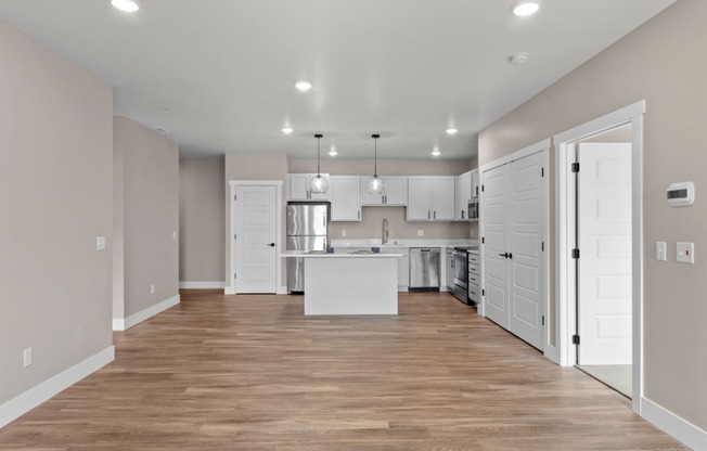 a kitchen and living room with a hardwood floor and white doors
