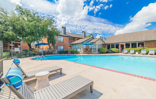 A pool with a bench and a tree in front of a house.