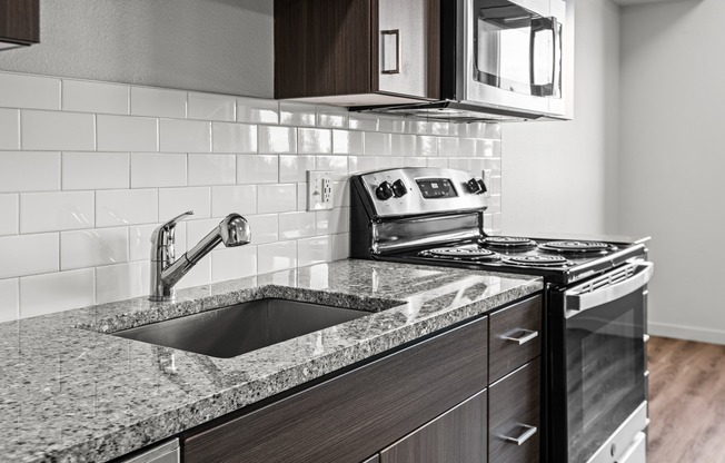 Modern kitchen with Stainless steel appliances, granite countertops, and durable wood-style plank flooring