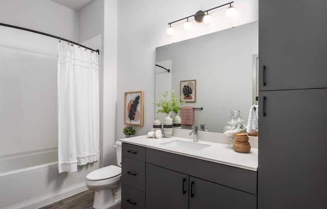 A bathroom with a white toilet, a white sink, and a white bathtub with a white shower curtain.