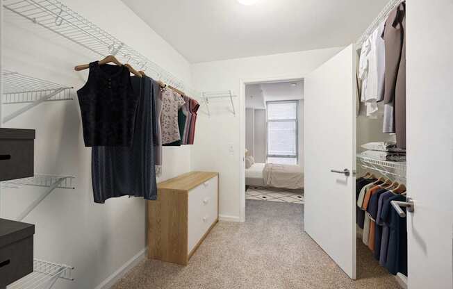 a walk in closet with clothes hanging on a rack and a door to a bedroom