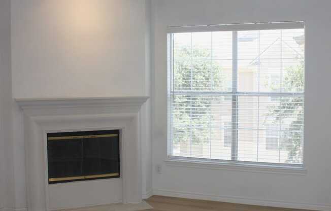 an empty living room with a fireplace and a ceiling fan