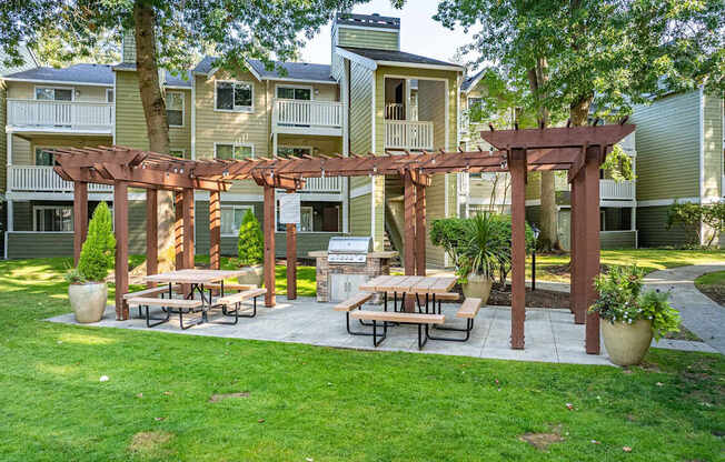 A patio with a pergola and benches is surrounded by apartment buildings.