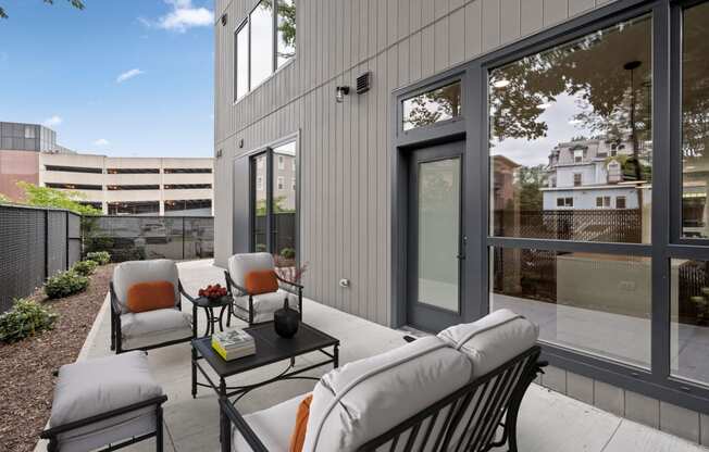 a patio with chairs and a table in front of a building