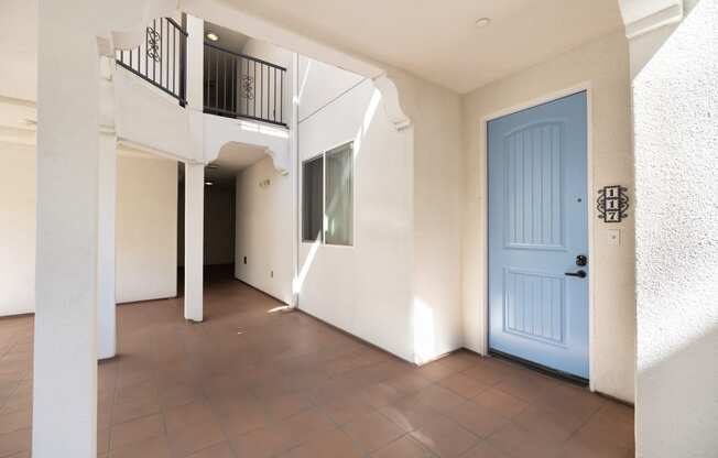 a room with a blue door and a tiled floor and a balcony