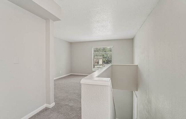 A white room with a window and a carpeted floor.