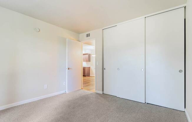 A white room with a carpeted floor and a white door.