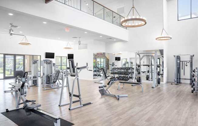 A spacious gym with a variety of equipment and a balcony overlooking the workout area.