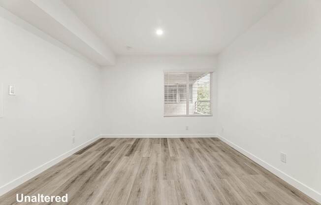 A room with unaltered wooden flooring and white walls.