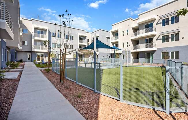 A tennis court is enclosed by a fence in a residential area.