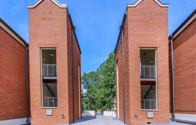 two red brick buildings with balconies and a blue sky