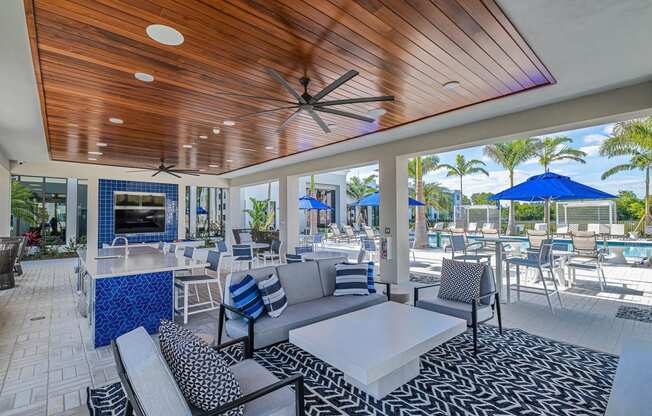 a patio with couches tables and chairs and a bar at Altis Santa Barbara, Florida, 34104