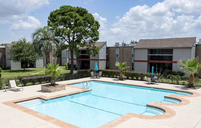 A swimming pool surrounded by palm trees and a building.