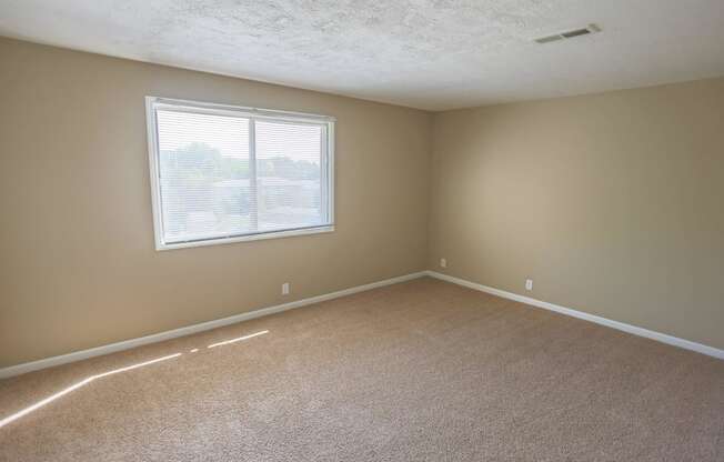 an empty living room with a window and carpet. Omaha, NE Evergreen Terrace Apartments