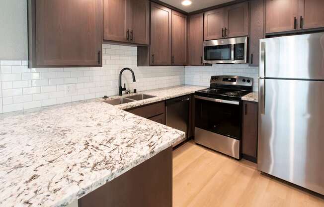 A kitchen with a granite counter top and stainless steel appliances.