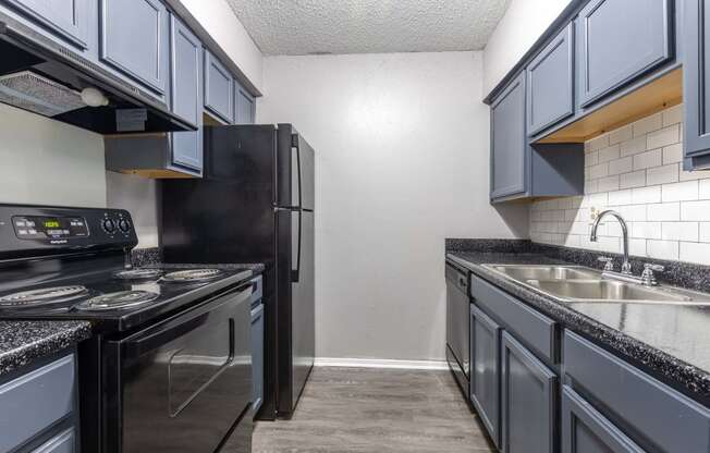 Whitney Manor Apartments in Gretna, LA photo of kitchen with black granite and blue cabinets