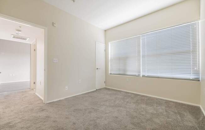 A room with a carpeted floor and a window with blinds.