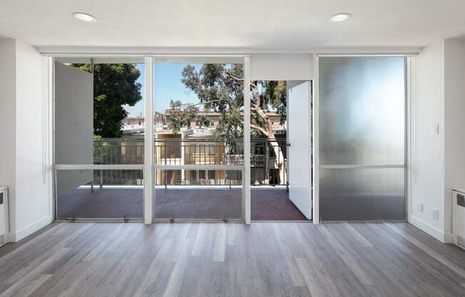 a living room with hardwood floors and glass doors leading to a balcony