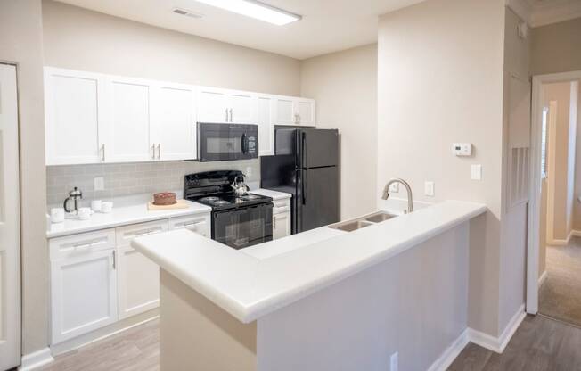 White Cabinetry and Black Appliances Kitchen with Breakfast Barat Polos at Hudson Corners Apartments, South Carolina 29650