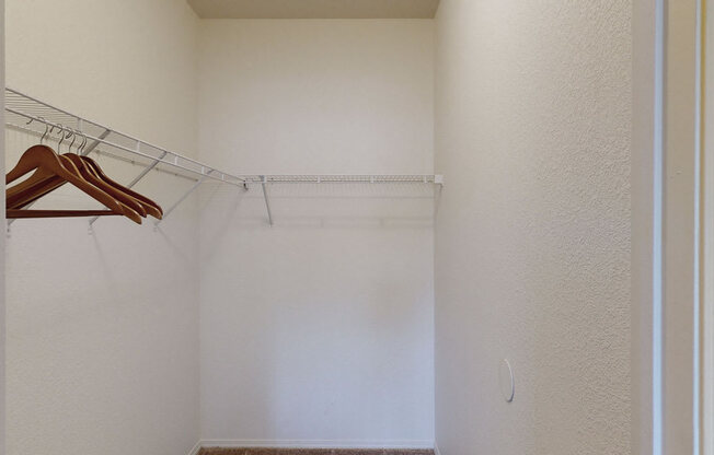 a walk in closet in a bedroom with white walls