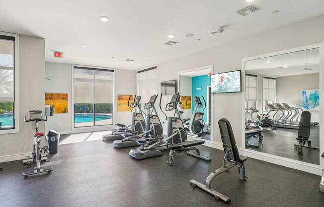 A gym with a variety of equipment including treadmills, stationary bikes, and weight machines.