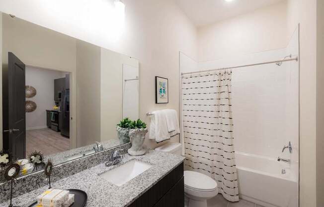 A bathroom with a white shower curtain and a white toilet.