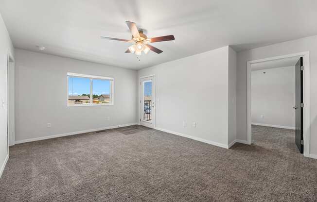 an empty living room with carpet and a ceiling fan