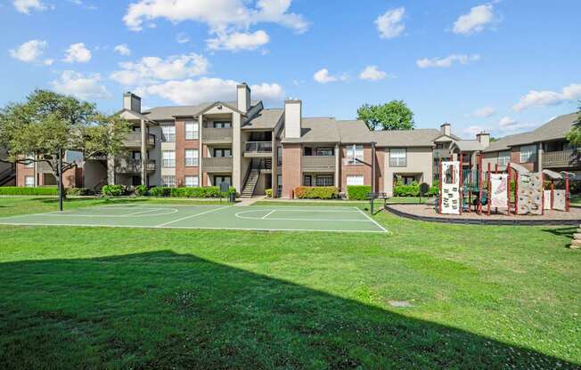 A basketball court is located in front of apartment buildings.