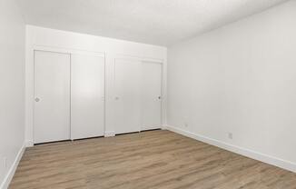 Three white doors in a room with wood flooring.