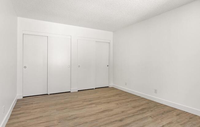Three white doors in a room with wood flooring.