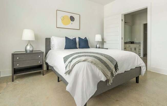 A bedroom with a bed, nightstand, and lamp.