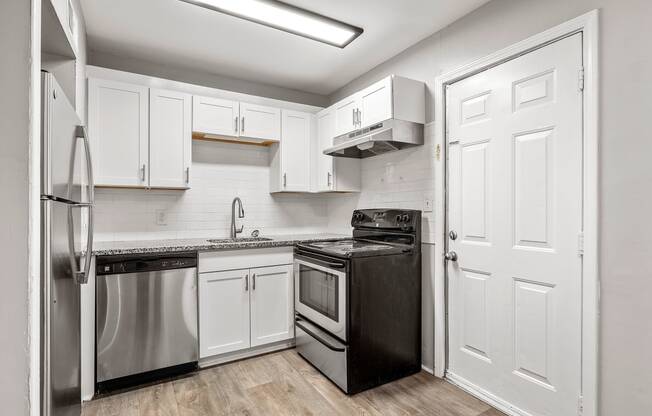 a white kitchen with stainless steel appliances and white cabinets