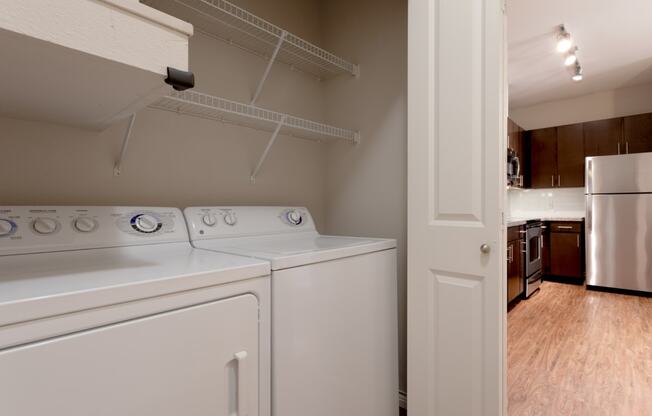 an empty laundry room with a white washer and dryer and a white refrigerator