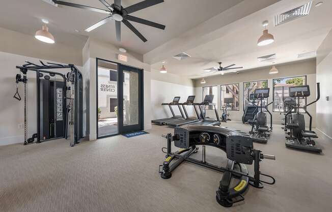 A gym with a variety of equipment including treadmills, weights, and a rowing machine.